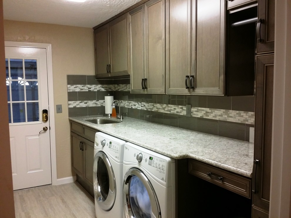 Mid-sized transitional single-wall utility room in Tampa with an undermount sink, medium wood cabinets, a side-by-side washer and dryer, recessed-panel cabinets, granite benchtops, beige walls, porcelain floors and beige floor.