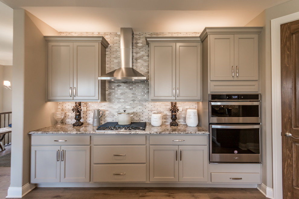 This is an example of a mid-sized traditional eat-in kitchen in Chicago with an undermount sink, flat-panel cabinets, brown cabinets, granite benchtops, grey splashback, marble splashback, stainless steel appliances, medium hardwood floors, with island, brown floor and grey benchtop.