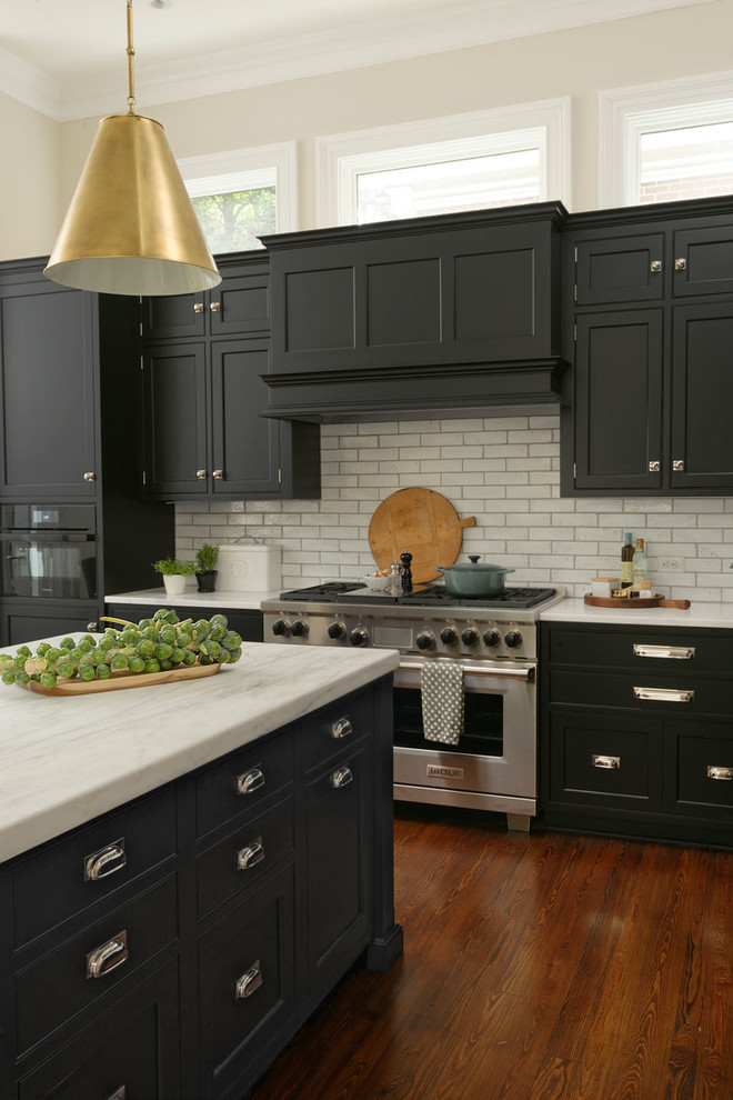 Inspiration for a large transitional l-shaped eat-in kitchen in DC Metro with a farmhouse sink, beaded inset cabinets, black cabinets, white splashback, subway tile splashback, stainless steel appliances, medium hardwood floors, with island, brown floor and quartzite benchtops.