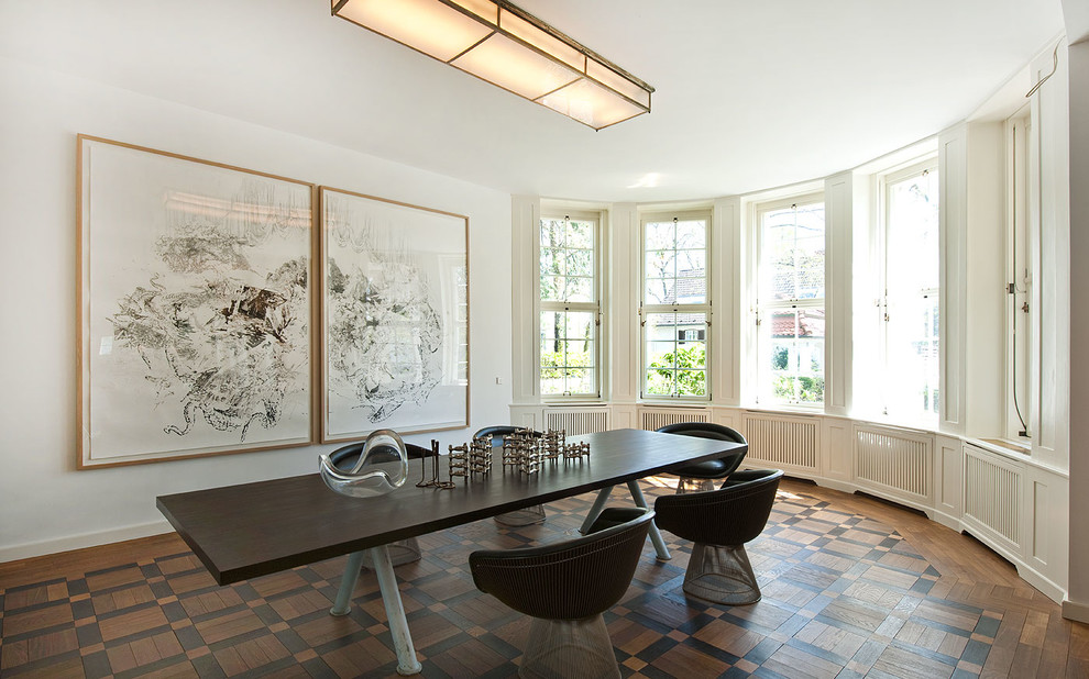 Large contemporary dining room in Berlin with white walls and dark hardwood floors.