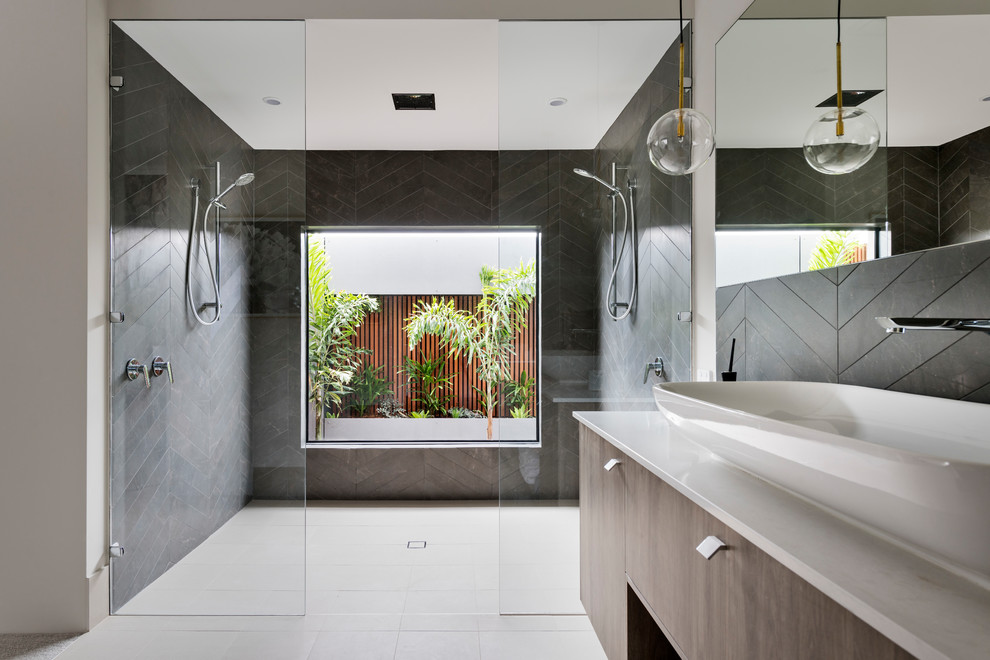 This is an example of a contemporary kids bathroom in Perth with flat-panel cabinets, medium wood cabinets, an alcove shower, black tile, beige walls, a vessel sink, beige floor, an open shower and beige benchtops.