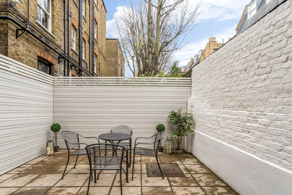 Inspiration for a small contemporary courtyard partial sun garden fence for summer in London with concrete paving and a wood fence.