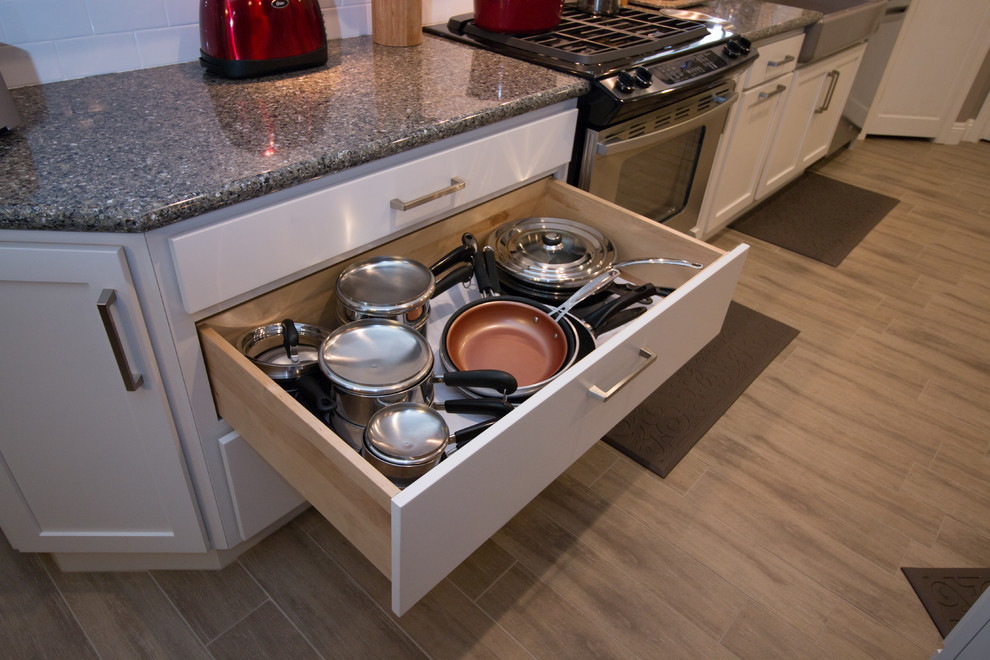 Open concept kitchen - mid-sized transitional galley porcelain tile open concept kitchen idea with a farmhouse sink, shaker cabinets, white cabinets, quartz countertops, white backsplash, subway tile backsplash and stainless steel appliances