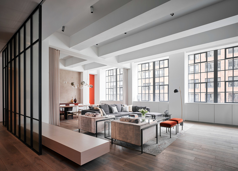 Example of an urban medium tone wood floor and brown floor living room design in New York with white walls