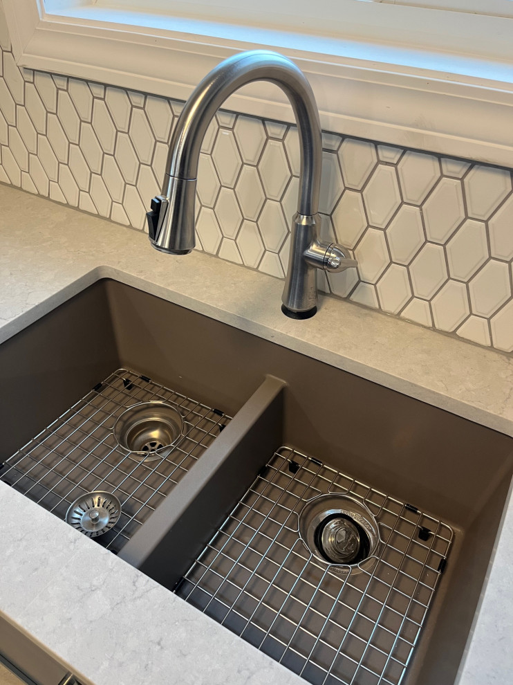 Mid-sized transitional u-shaped vinyl floor and brown floor eat-in kitchen photo with an undermount sink, shaker cabinets, white cabinets, quartz countertops, white backsplash, ceramic backsplash, stainless steel appliances, no island and white countertops