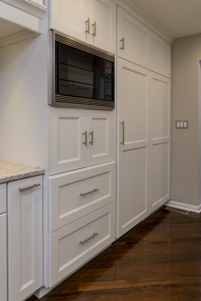 Mid-sized transitional galley medium tone wood floor home design photo in Chicago with an undermount sink, flat-panel cabinets, white cabinets, quartz countertops, beige backsplash, glass tile backsplash, paneled appliances and a peninsula