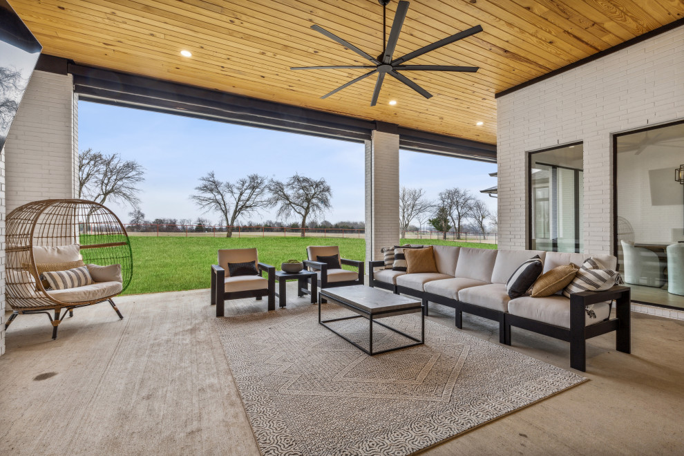 Photo of an expansive contemporary back patio in Dallas with a fireplace, concrete slabs and a roof extension.