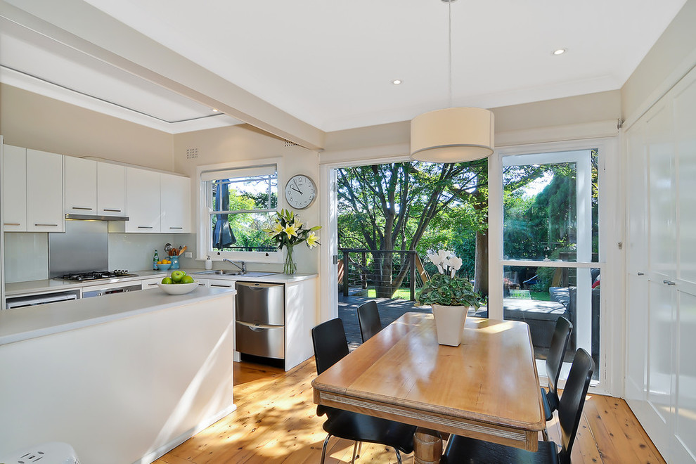 Inspiration for a small modern l-shaped eat-in kitchen in Sydney with a peninsula, flat-panel cabinets, white cabinets, laminate benchtops, beige splashback, glass sheet splashback, stainless steel appliances, a double-bowl sink, light hardwood floors and orange floor.