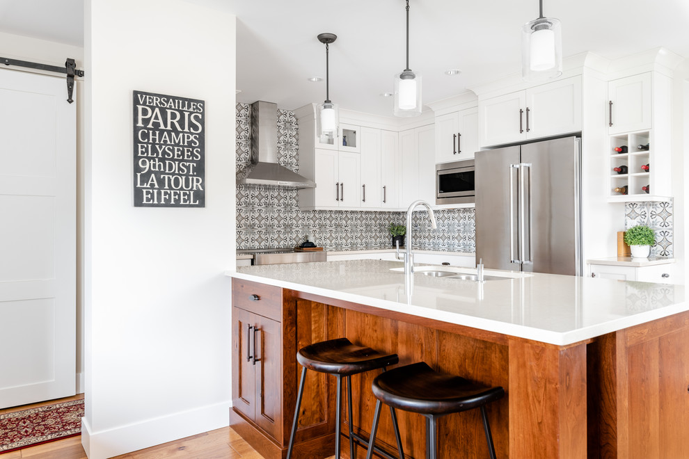 Kitchen - mid-sized transitional l-shaped medium tone wood floor and brown floor kitchen idea with an undermount sink, shaker cabinets, white cabinets, quartzite countertops, gray backsplash, porcelain backsplash, stainless steel appliances, an island and white countertops