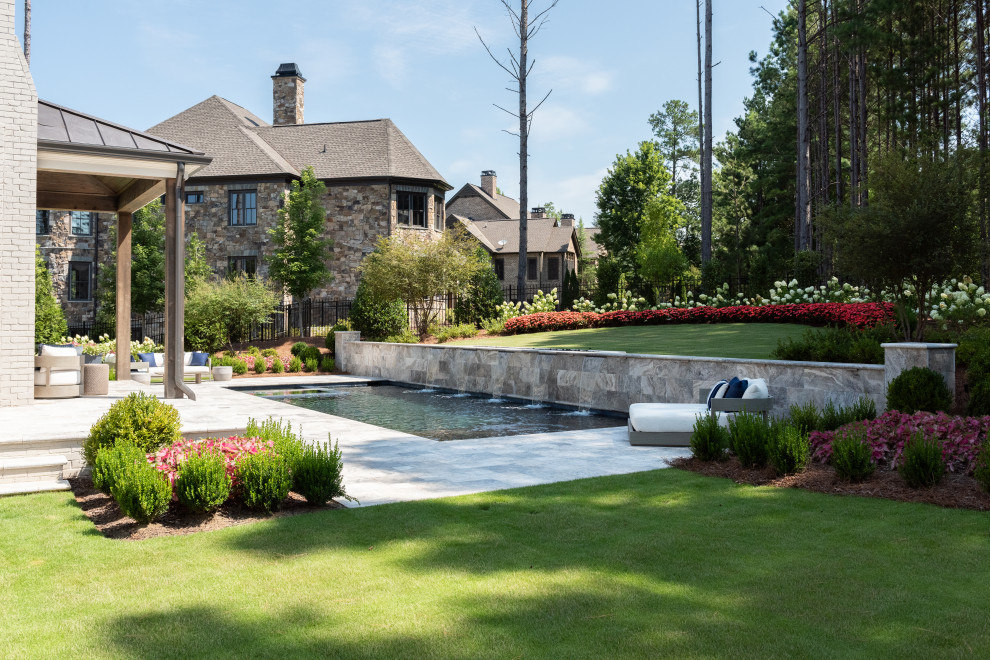Imagen de piscina con fuente actual grande rectangular en patio trasero con adoquines de piedra natural