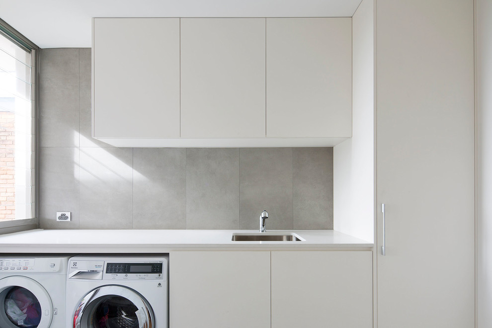 Inspiration for a mid-sized modern galley dedicated laundry room in Sydney with an undermount sink, flat-panel cabinets, white cabinets, quartz benchtops and a side-by-side washer and dryer.