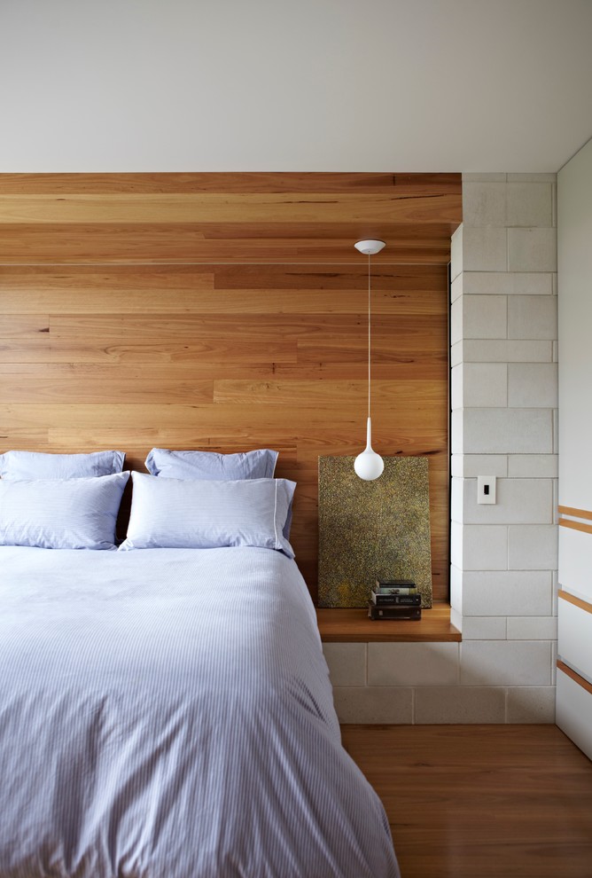 This is an example of a contemporary bedroom in Brisbane with white walls and medium hardwood floors.