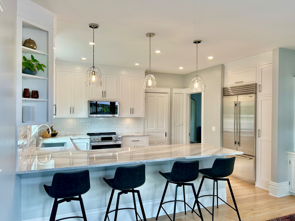 Mid-sized transitional u-shaped light wood floor and beige floor open concept kitchen photo with an undermount sink, beaded inset cabinets, white cabinets, quartz countertops, white backsplash, ceramic backsplash, stainless steel appliances, a peninsula and white countertops