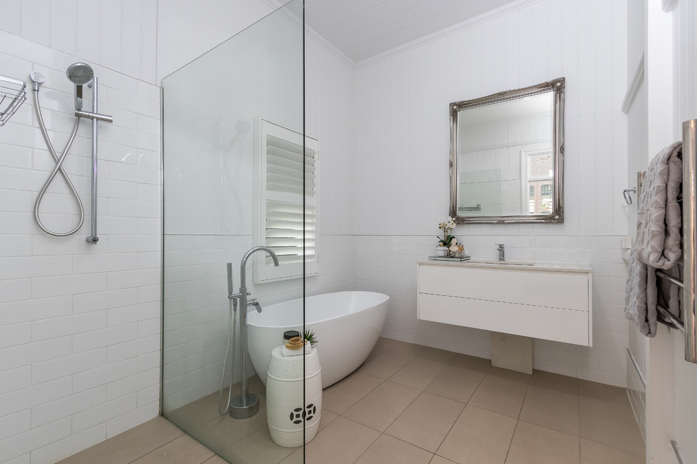Inspiration for a beach style bathroom in Brisbane with flat-panel cabinets, white cabinets, a freestanding tub, a corner shower, white tile, white walls, an undermount sink, grey floor, an open shower and white benchtops.