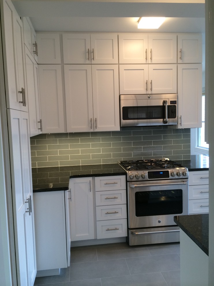 Example of a mid-sized transitional u-shaped porcelain tile enclosed kitchen design in Orange County with an undermount sink, shaker cabinets, white cabinets, granite countertops, gray backsplash, ceramic backsplash, stainless steel appliances and no island
