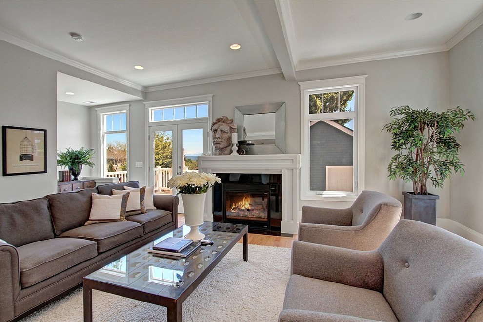 Photo of a mid-sized traditional formal open concept living room in Seattle with grey walls, light hardwood floors, a standard fireplace, a plaster fireplace surround and no tv.
