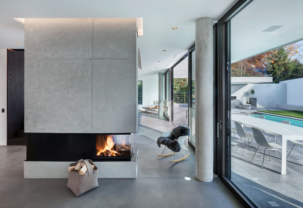 Expansive modern formal loft-style living room in Munich with white walls, linoleum floors, a two-sided fireplace, a concrete fireplace surround, no tv and grey floor.
