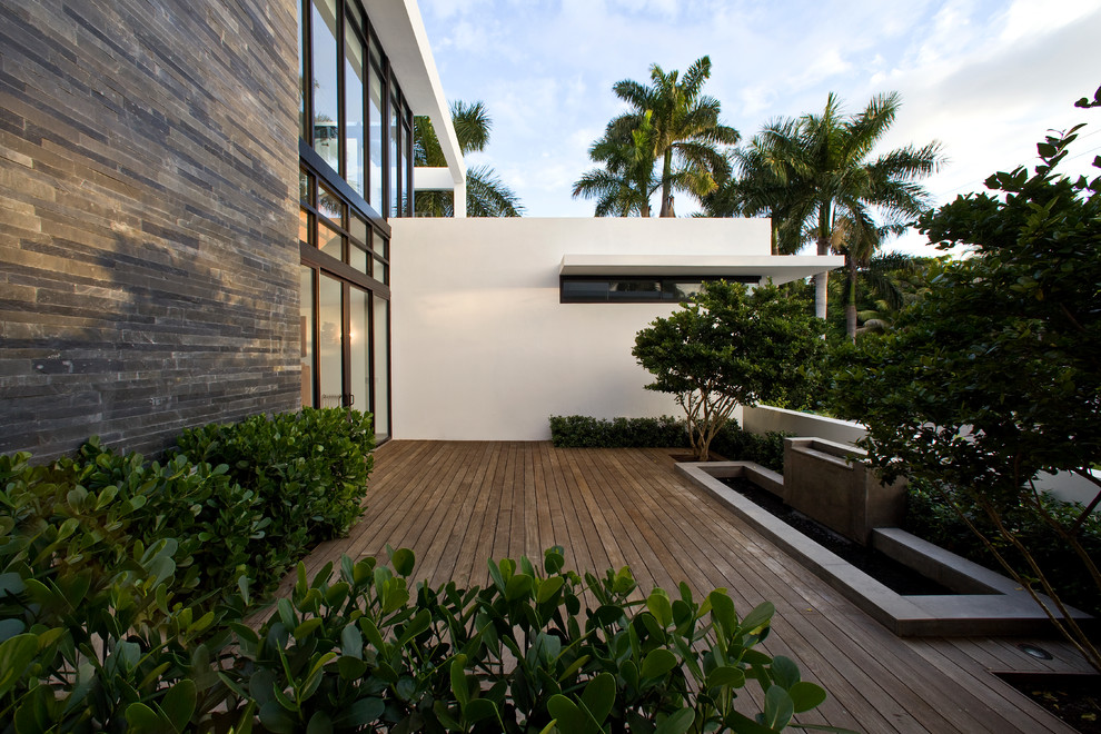 This is an example of a contemporary deck in Miami with a water feature and no cover.