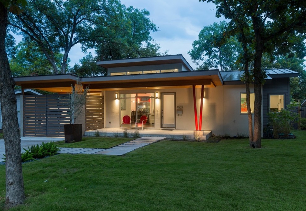 Photo of a small contemporary one-storey stucco grey house exterior in Austin with a flat roof and a metal roof.