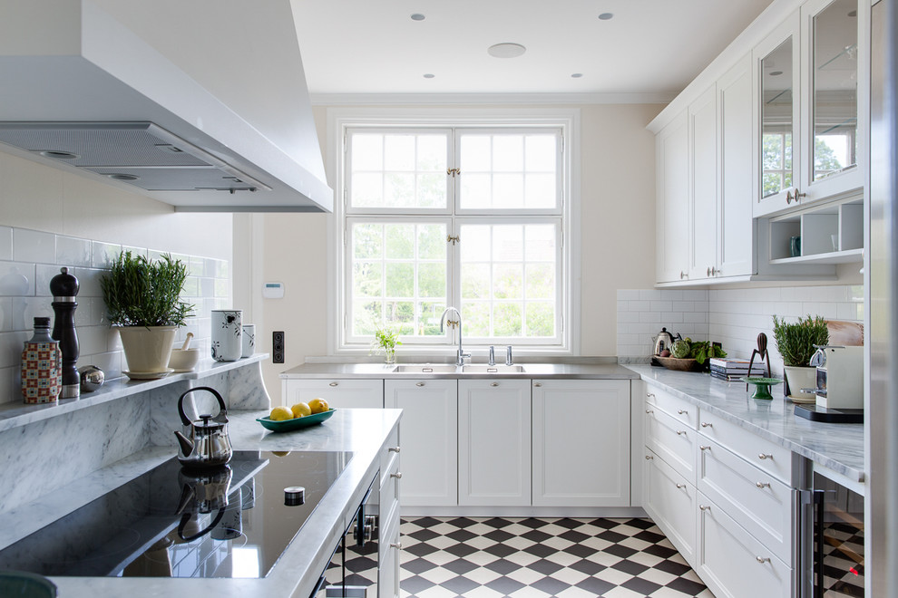 Mid-sized transitional l-shaped separate kitchen in Malmo with a double-bowl sink, recessed-panel cabinets, white cabinets, white splashback, stainless steel appliances, no island, marble benchtops and ceramic floors.