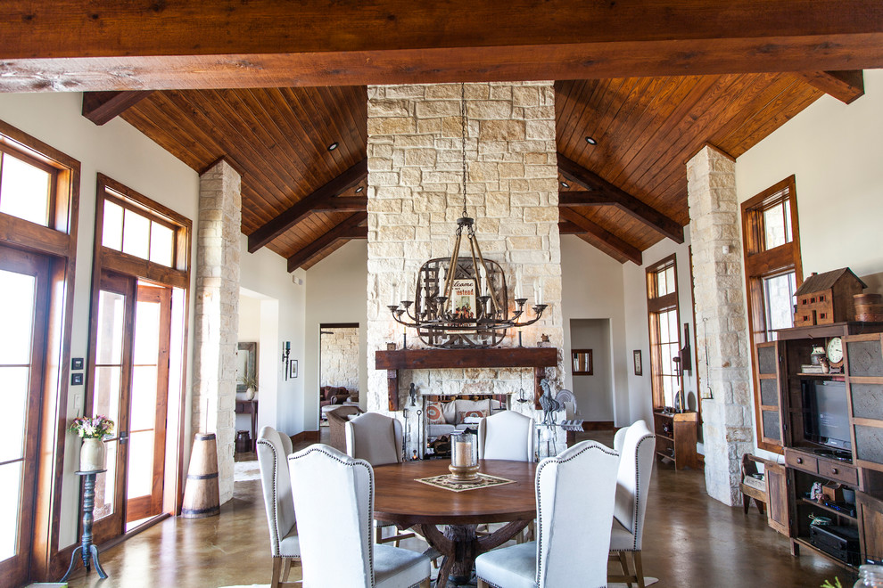 Inspiration for a large arts and crafts kitchen/dining combo in Houston with a two-sided fireplace, a stone fireplace surround, concrete floors, white walls, brown floor and vaulted.