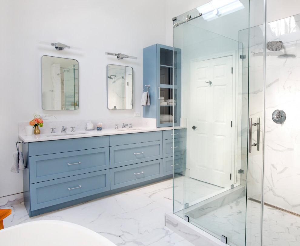 This is an example of a medium sized contemporary grey and white ensuite half tiled bathroom in New York with recessed-panel cabinets, blue cabinets, a freestanding bath, a double shower, a one-piece toilet, white walls, a submerged sink, multi-coloured floors, a sliding door, a shower bench, double sinks, a built in vanity unit, black and white tiles, porcelain tiles, porcelain flooring, engineered stone worktops and multi-coloured worktops.