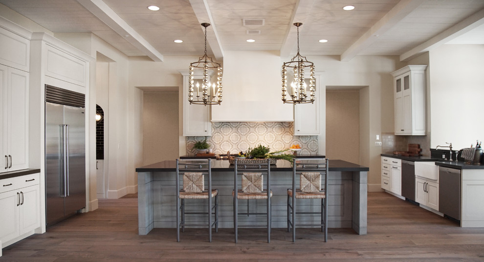 Photo of a large transitional u-shaped open plan kitchen in Phoenix with a farmhouse sink, shaker cabinets, grey cabinets, quartz benchtops, multi-coloured splashback, terra-cotta splashback, stainless steel appliances, medium hardwood floors, with island, brown floor, black benchtop and wood.