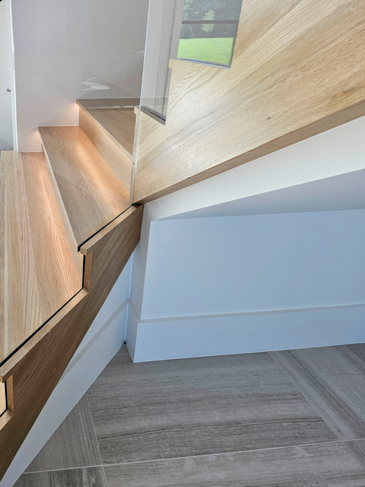 Idées déco pour un très grand escalier flottant contemporain avec des marches en bois, des contremarches en bois, un garde-corps en matériaux mixtes et boiseries.