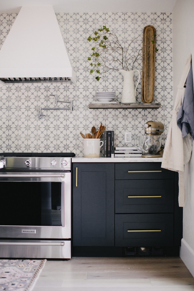 Inspiration for a large transitional light wood floor eat-in kitchen remodel with a farmhouse sink, shaker cabinets, black cabinets, quartzite countertops, cement tile backsplash, stainless steel appliances and an island