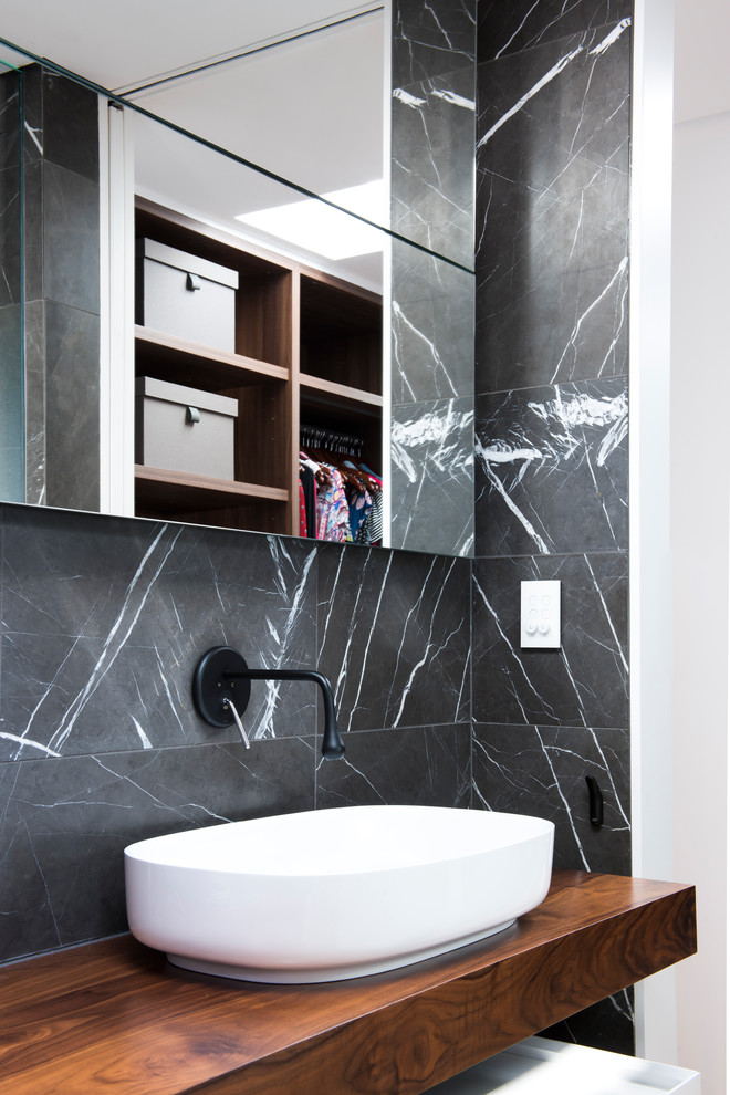 Photo of a small modern master bathroom in Sydney with furniture-like cabinets, white cabinets, an open shower, a wall-mount toilet, gray tile, stone tile, grey walls, light hardwood floors, a vessel sink, wood benchtops and an open shower.