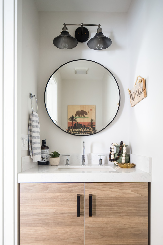 Design ideas for a beach style powder room in Orange County with flat-panel cabinets, light wood cabinets, white walls and white benchtops.