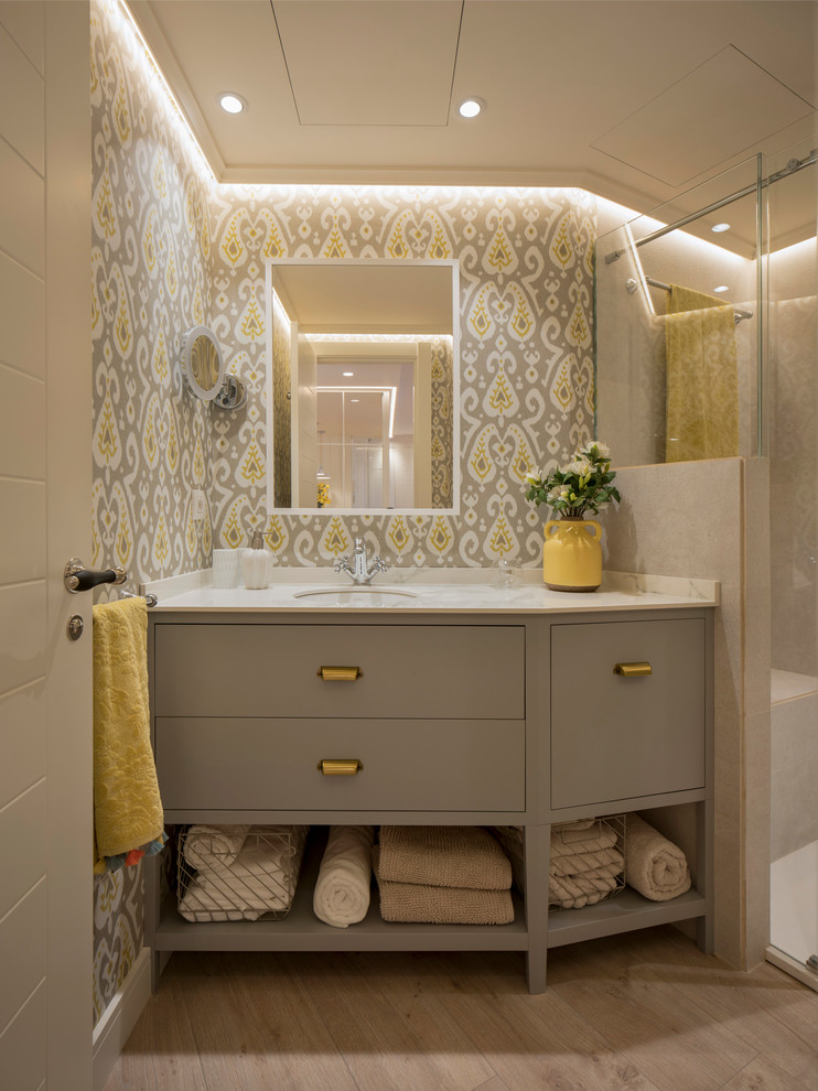 Large transitional 3/4 bathroom in Bilbao with flat-panel cabinets, light wood cabinets, a curbless shower, a wall-mount toilet, beige tile, ceramic tile, beige walls, laminate floors, engineered quartz benchtops, beige floor, a sliding shower screen and an undermount sink.