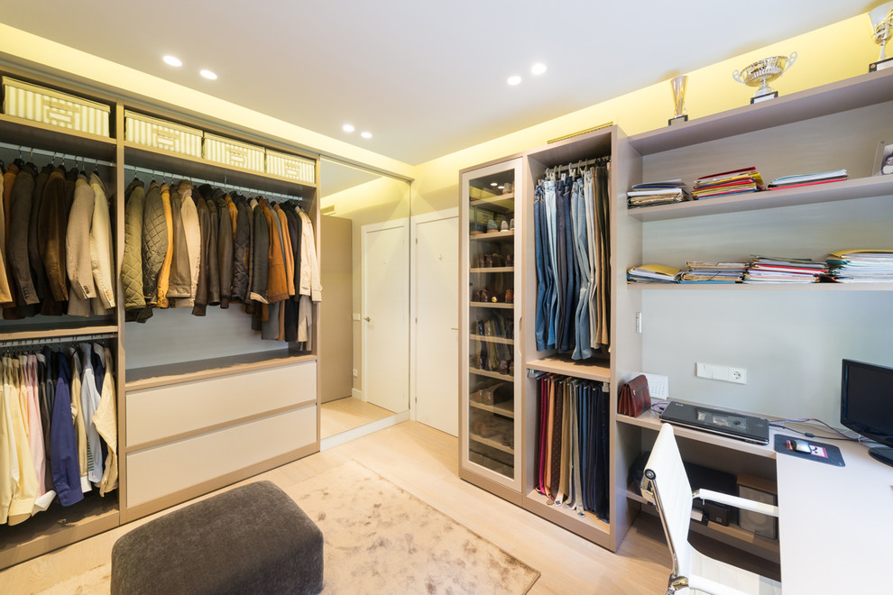 Photo of a mid-sized transitional gender-neutral built-in wardrobe in Barcelona with open cabinets, light hardwood floors and beige floor.