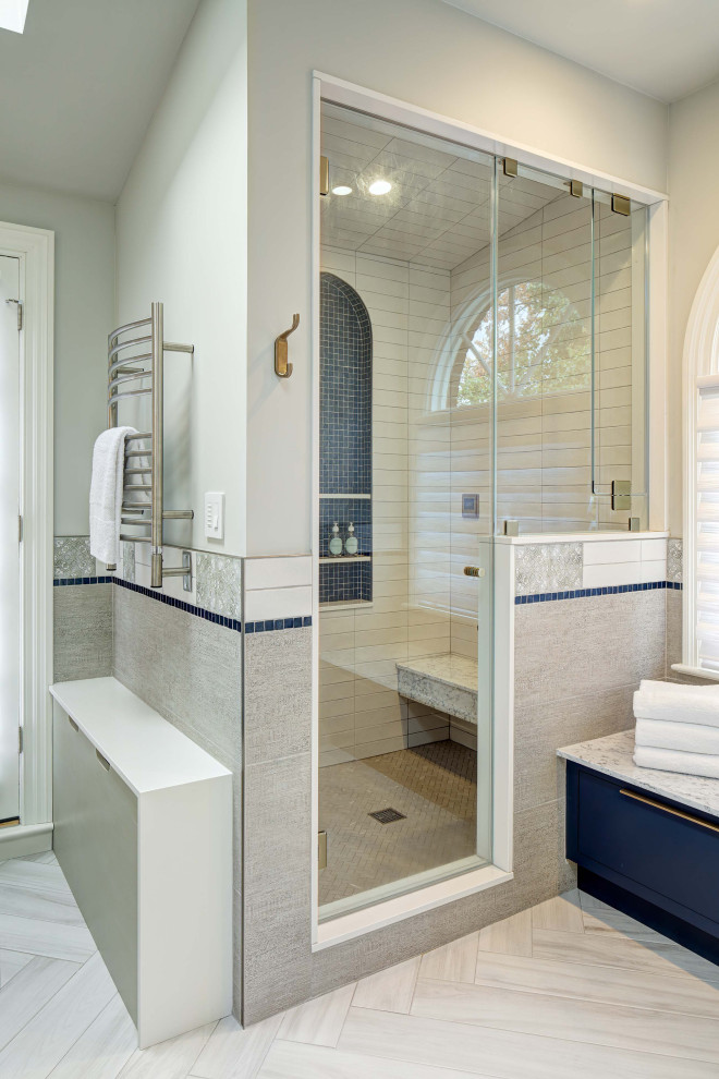 Cette photo montre une grande douche en alcôve principale éclectique avec un placard à porte plane, des portes de placard bleues, un bidet, un carrelage gris, des carreaux de porcelaine, un mur gris, un sol en carrelage de porcelaine, un plan de toilette en marbre, un sol gris, une cabine de douche à porte battante, un plan de toilette blanc, un banc de douche, meuble double vasque, meuble-lavabo sur pied et un plafond voûté.