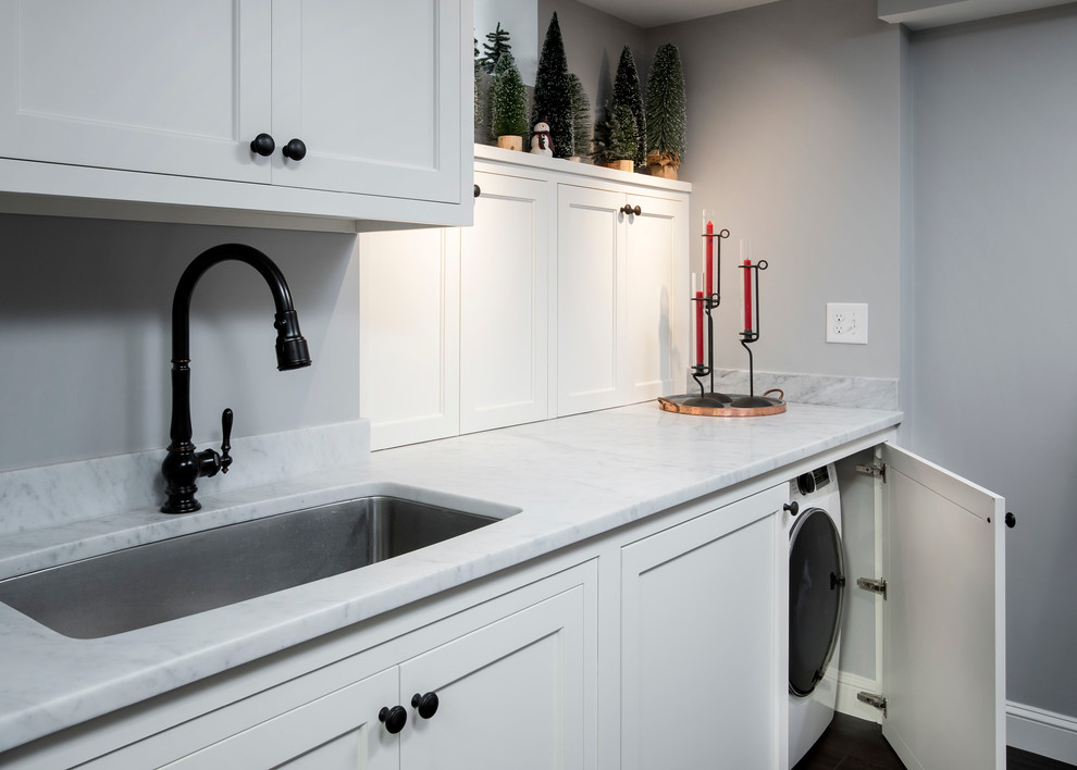 Small traditional single-wall utility room in Boston with an undermount sink, shaker cabinets, white cabinets, marble benchtops, blue walls, vinyl floors and a side-by-side washer and dryer.