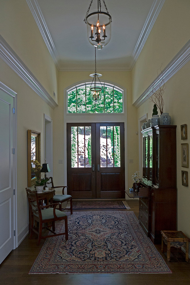 Design ideas for a large traditional foyer in Raleigh with yellow walls, dark hardwood floors, a double front door and a light wood front door.