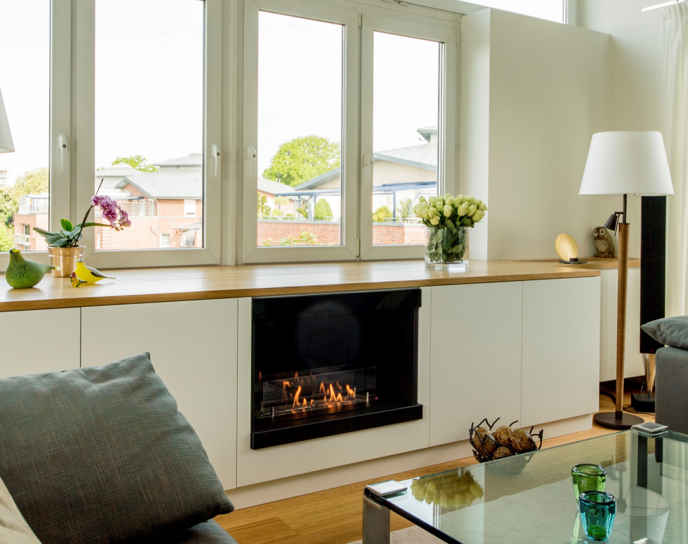 Große, Offene Klassische Bibliothek mit beiger Wandfarbe, hellem Holzboden, Kamin, Kaminumrandung aus Holz, verstecktem TV, braunem Boden, gewölbter Decke und Tapetenwänden in Hannover