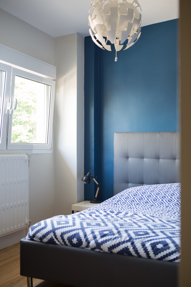 Diseño de dormitorio principal contemporáneo de tamaño medio con paredes azules y suelo de madera clara