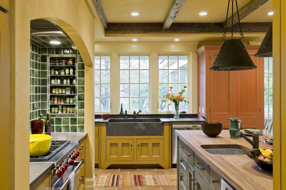 Photo of a traditional kitchen in Burlington with stainless steel appliances, an integrated sink, wood benchtops, yellow cabinets and green splashback.