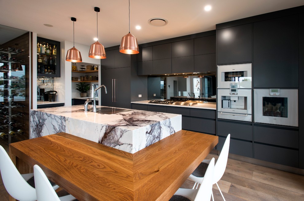 Inspiration for a contemporary l-shaped kitchen in Brisbane with grey cabinets, marble benchtops, mirror splashback, with island, medium hardwood floors, an undermount sink, flat-panel cabinets, white appliances, brown floor and white benchtop.
