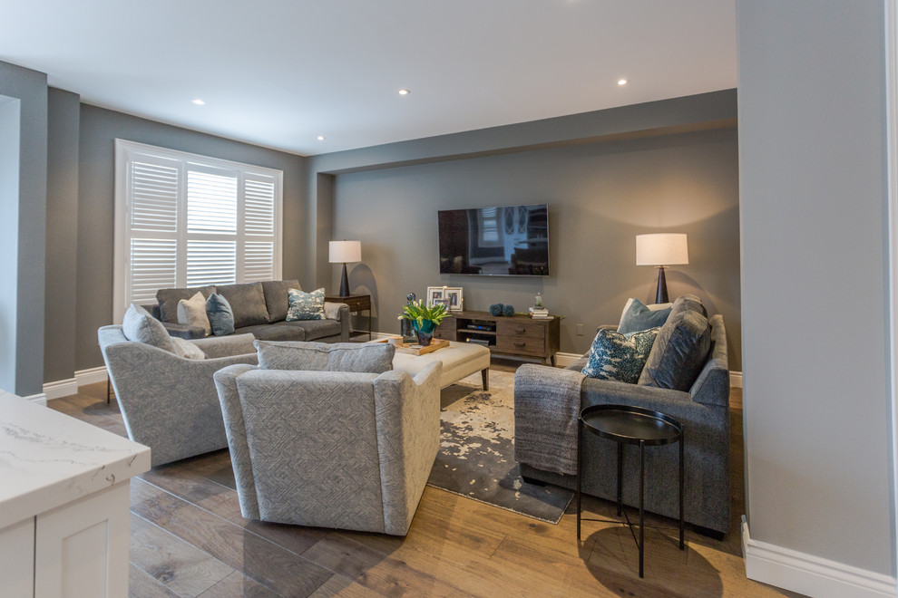 This is an example of a large contemporary open concept family room in Toronto with grey walls, medium hardwood floors, no fireplace, a wall-mounted tv and brown floor.