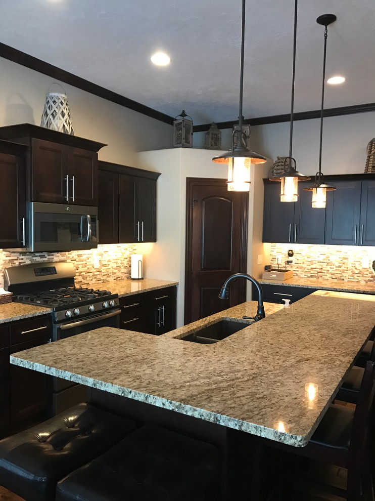Transitional l-shaped kitchen photo with an undermount sink, flat-panel cabinets, dark wood cabinets, granite countertops, multicolored backsplash, ceramic backsplash, stainless steel appliances and an island