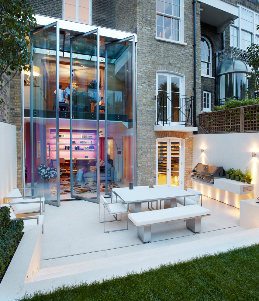 Large contemporary backyard patio in London with no cover.
