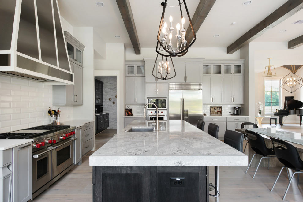 Country l-shaped light wood floor and beige floor open concept kitchen photo in Houston with an undermount sink, shaker cabinets, gray cabinets, white backsplash, subway tile backsplash, stainless steel appliances, an island and gray countertops