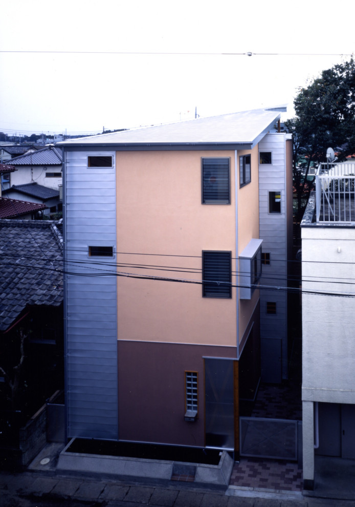 Пример оригинального дизайна: трехэтажный, оранжевый частный загородный дом среднего размера в стиле модернизм с вальмовой крышей, металлической крышей, серой крышей и облицовкой из цементной штукатурки