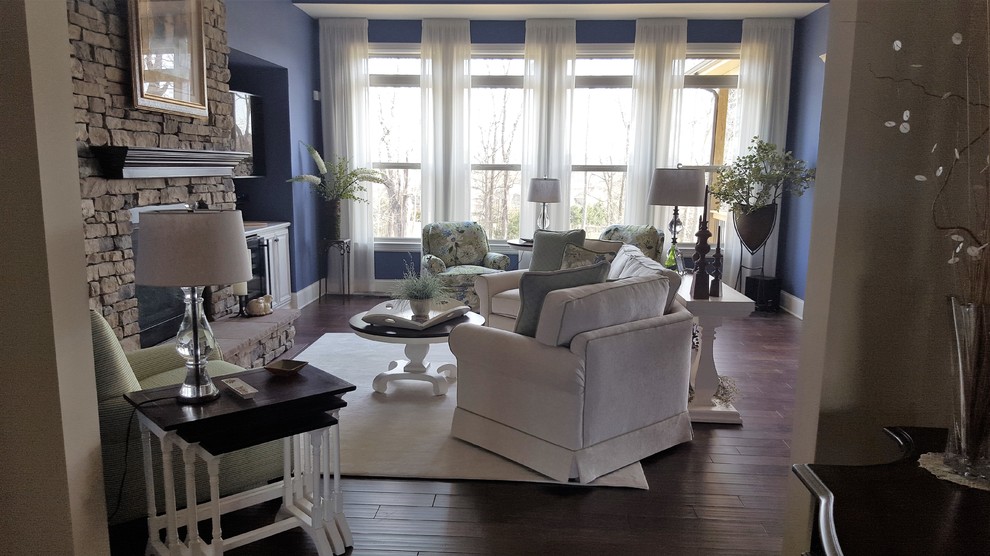 Design ideas for a mid-sized transitional formal enclosed living room in Nashville with blue walls, dark hardwood floors, a standard fireplace, a stone fireplace surround, a wall-mounted tv and brown floor.