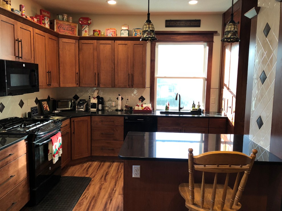Enclosed kitchen - small craftsman u-shaped vinyl floor and brown floor enclosed kitchen idea in Cedar Rapids with an undermount sink, flat-panel cabinets, brown cabinets, quartzite countertops, white backsplash, porcelain backsplash, black appliances, a peninsula and black countertops