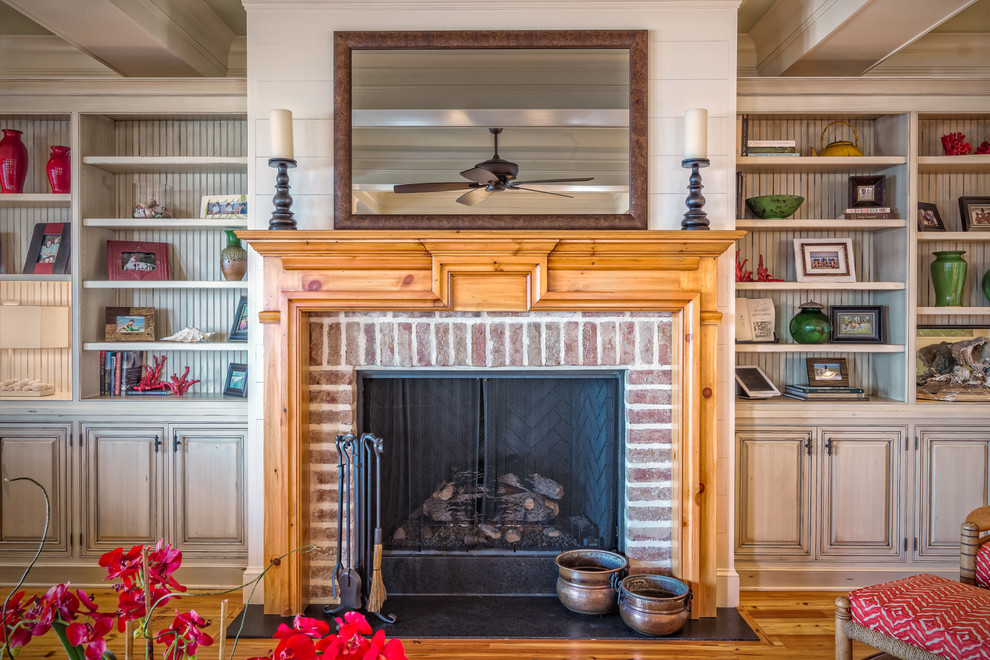 Inspiration for a large traditional open concept living room in Charleston with green walls, medium hardwood floors, a standard fireplace, a brick fireplace surround, a concealed tv and a home bar.
