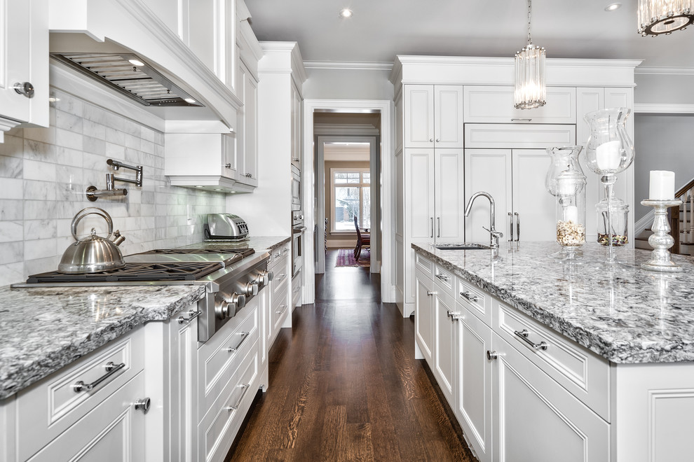 Open concept kitchen - large transitional u-shaped dark wood floor and brown floor open concept kitchen idea in Toronto with an undermount sink, beaded inset cabinets, white cabinets, granite countertops, gray backsplash, marble backsplash, paneled appliances, an island and multicolored countertops