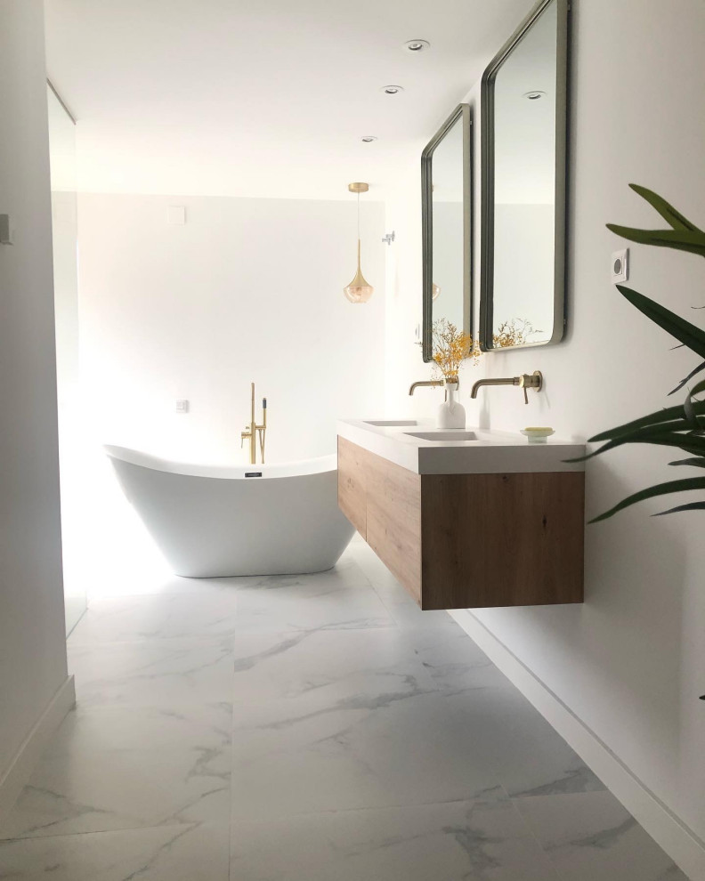 This is an example of an expansive modern grey and white ensuite bathroom with freestanding cabinets, white cabinets, a freestanding bath, a built-in shower, all types of toilet, multi-coloured tiles, white walls, ceramic flooring, a wall-mounted sink, soapstone worktops, multi-coloured floors, an open shower, white worktops, an enclosed toilet, double sinks, a floating vanity unit, all types of ceiling and all types of wall treatment.